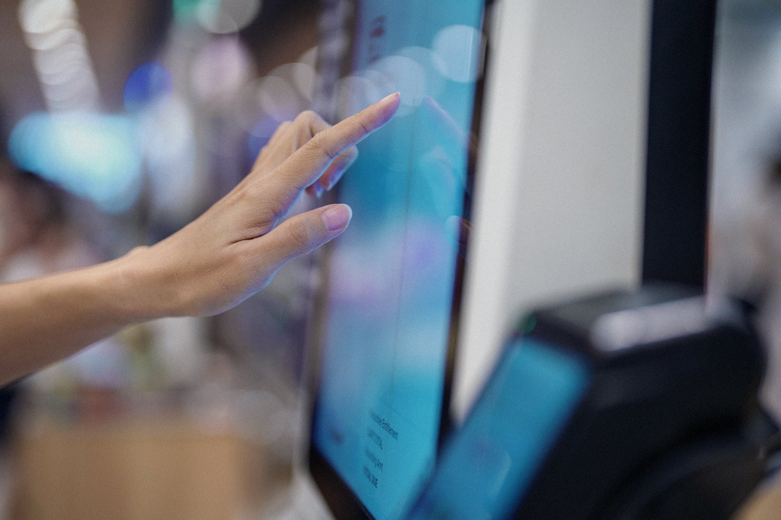 Hand tapping a POS touchscreen beside a card terminal
